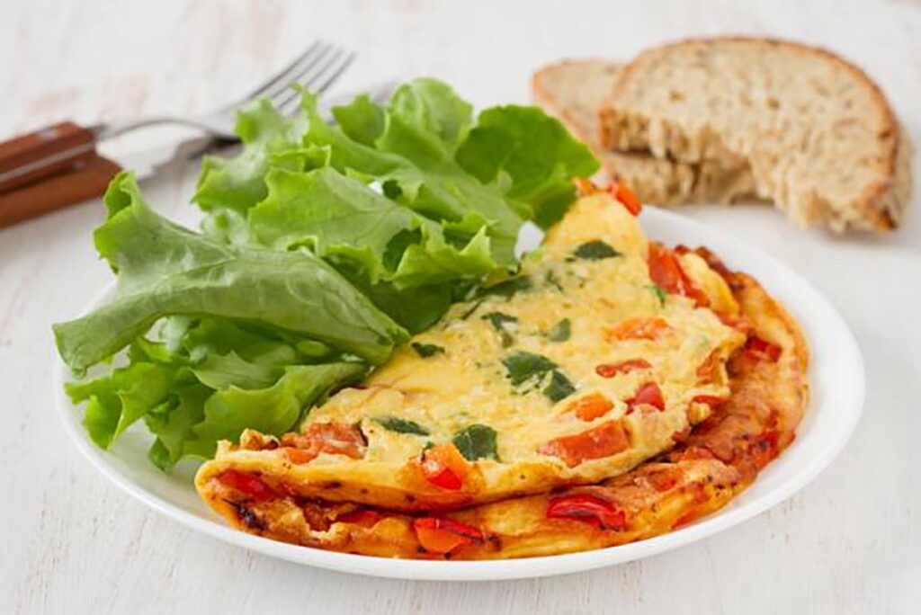 A delicious spinach vegetarian omelette served on a plate, garnished with fresh herbs and vegetables.