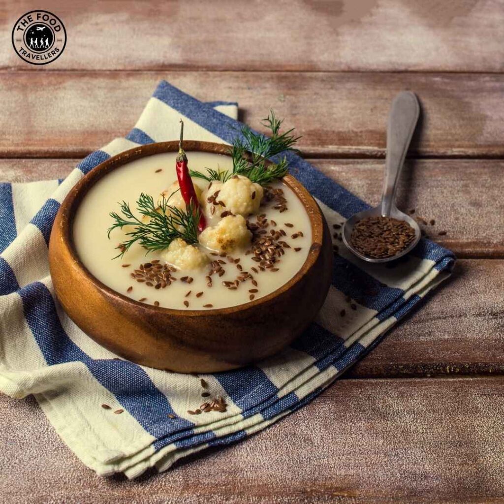 Close-up of creamy cauliflower soup in a bowl, topped with fresh herbs and a drizzle of olive oil.