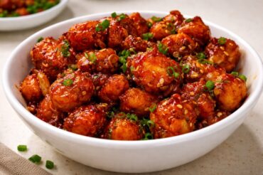 Crispy honey chilli baby corn tossed in sweet and spicy sauce garnished with sesame seeds and spring onions