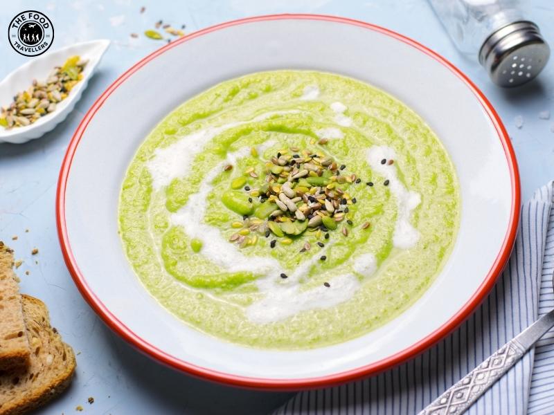 Close-up of a bowl of creamy Cheesy Zucchini Soup, with a smooth texture and a sprinkle of cheese and herbs on top.
