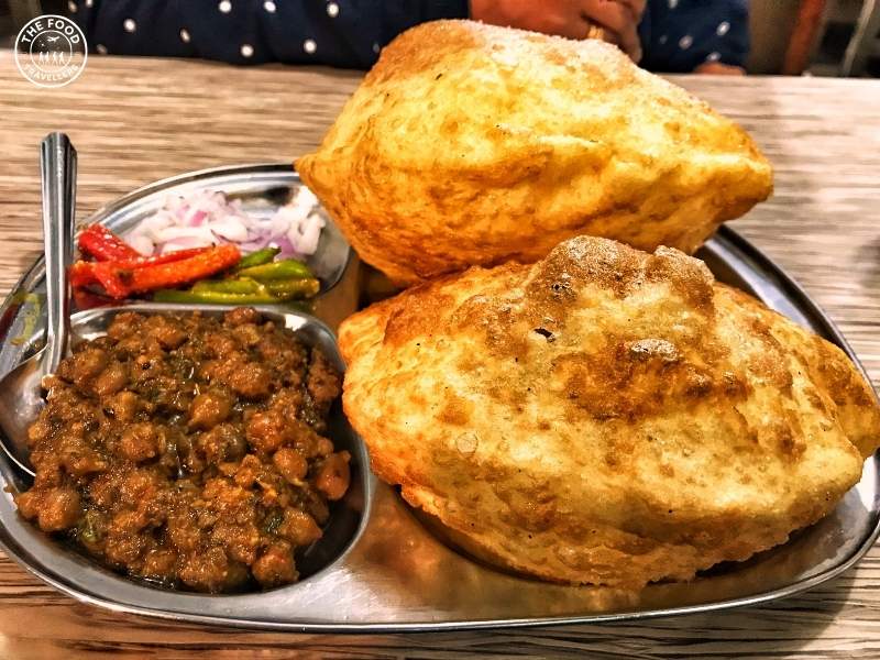 A plate of Chole Bhature featuring spicy chickpea curry served with fluffy, golden-brown deep-fried bhature bread