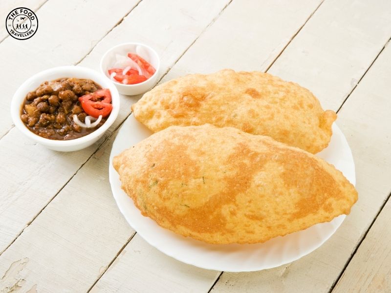 A serving of spicy chole (chickpea curry) paired with fluffy, golden-brown bhature bread, ready to be enjoyed.