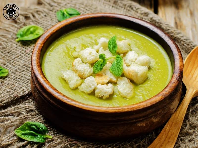 Close-up of a creamy bowl of Cheesy Zucchini Soup, featuring a smooth texture with a sprinkle of grated cheese and fresh herbs on top.