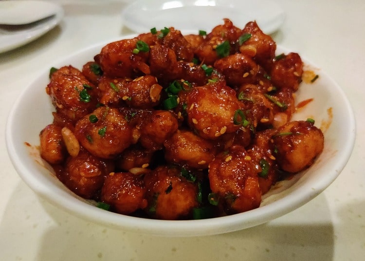 Crispy baby corn coated in a sweet and spicy honey chilli sauce, garnished with fresh herbs.