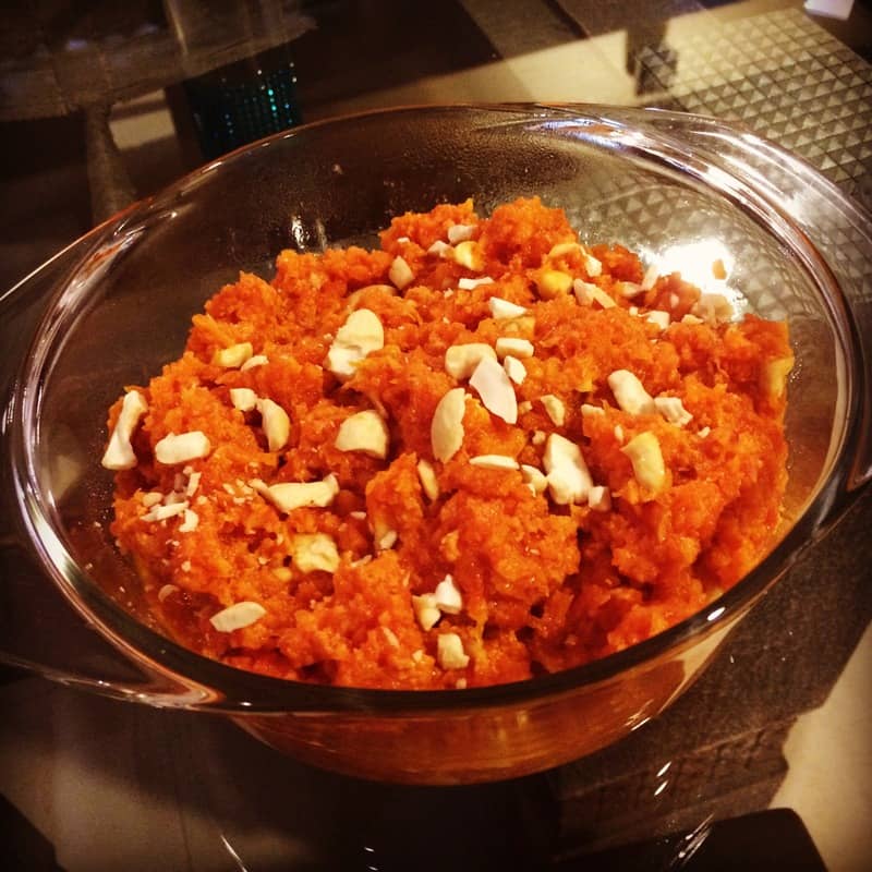 A bowl of gajar ka halwa garnished with nuts, showcasing its rich, vibrant orange color and creamy texture.