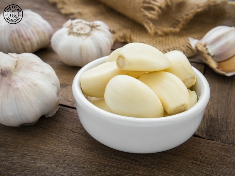 Freshly peeled garlic cloves in a small bowl, displaying their smooth texture and natural shine.