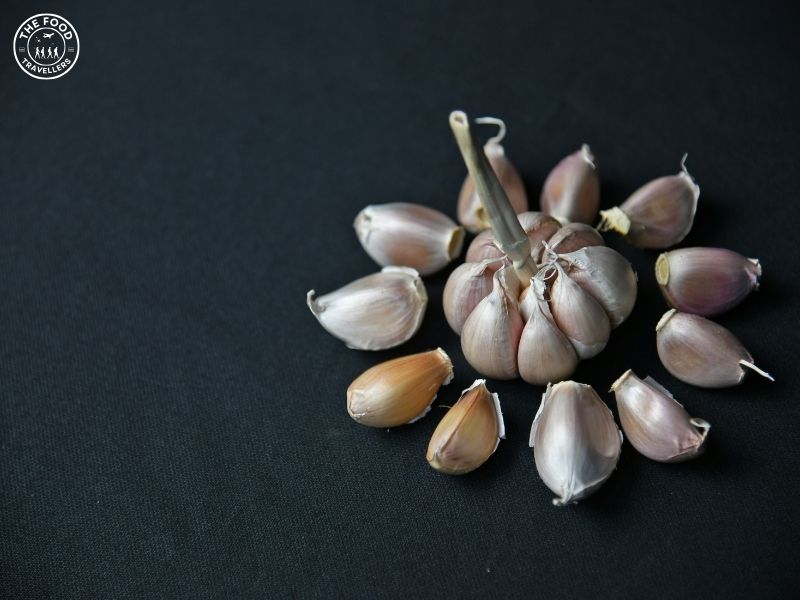 Close-up of garlic pods, showcasing their individual cloves and papery skin, highlighting the natural texture and structure of garlic.