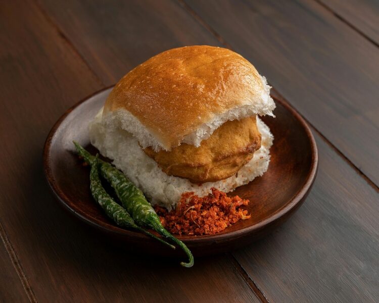 Vada Pav Aamchi Mumbai, featuring a crispy potato fritter in soft pav with tangy chutneys, a true taste of Mumbai street food.