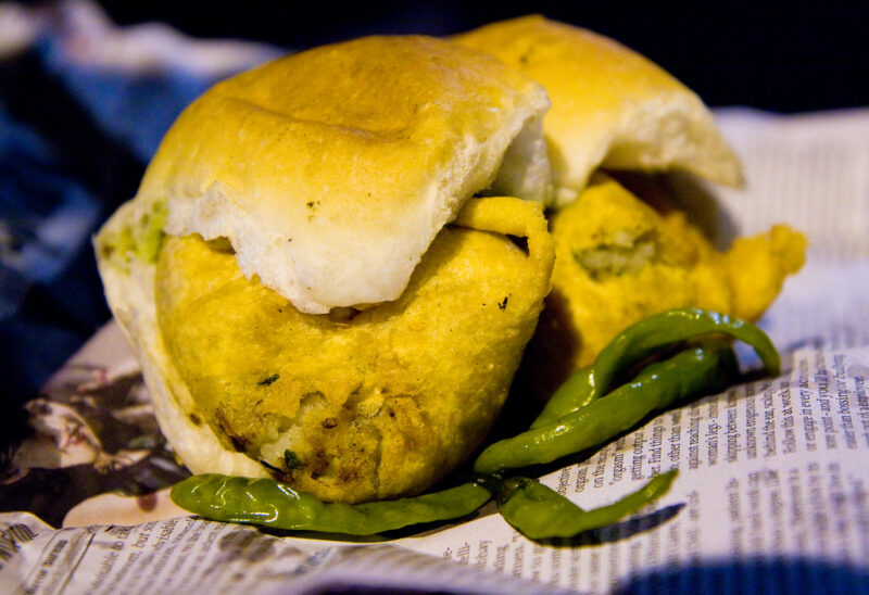 Authentic Vada Pav from Mumbai, featuring a crispy potato fritter in a soft pav with chutneys and green chili.