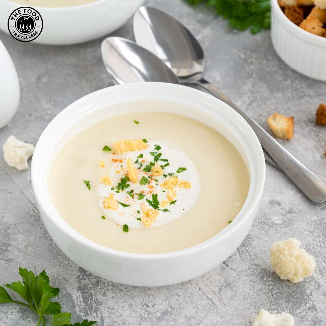 A bowl of creamy vegetarian cauliflower soup garnished with herbs, served warm and inviting.