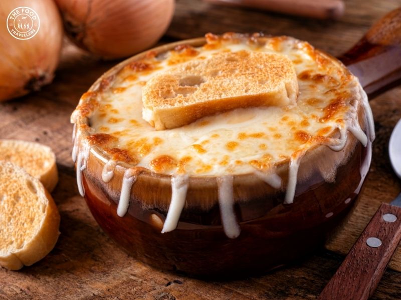 A bowl of vegetarian French onion soup, with caramelized onions and a golden, melted cheese topping.
