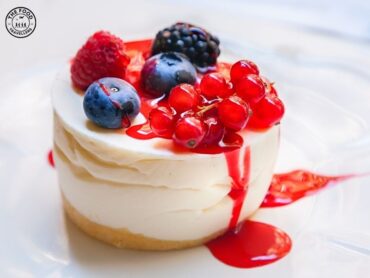 Vegetarian Panna Cotta served in a glass, topped with fresh berries and a mint leaf, showcasing its creamy texture.