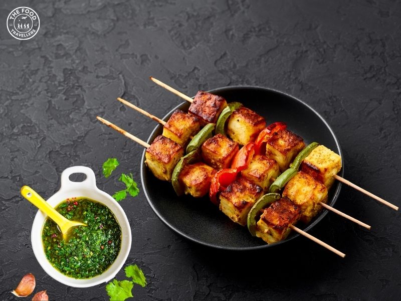 "Grilled Chimichurri Paneer Tikka served on a sizzling plate, garnished with fresh cilantro.