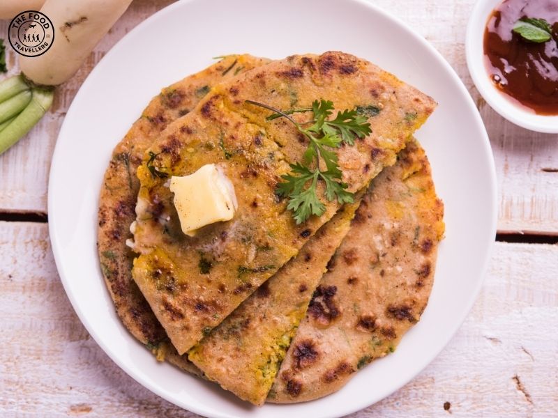 "Close-up of a golden-brown Pyaz Paratha served with a dollop of butter.