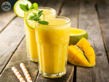 A vibrant Sunburst Smoothie in a glass, featuring a bright orange color with a refreshing blend of fruits, garnished with a slice of citrus and a sprig of mint.