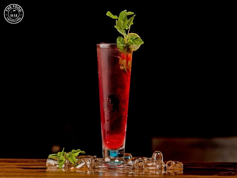 A vibrant Sweet Tomato Basil Mocktail in a glass, garnished with fresh basil leaves offering a refreshing blend of flavors.