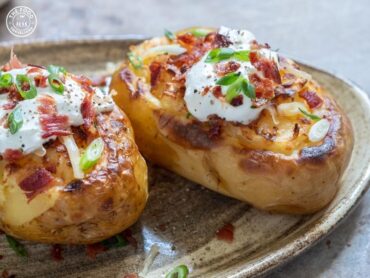 A plated Veg Baked Potato, topped with a savory mix of vegetables, cheese, and herbs, baked to a crispy perfection.