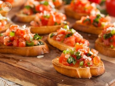 A plate of Veg Bruschetta, featuring toasted bread topped with a colorful mix of fresh tomatoes, basil, garlic, and olive oil.