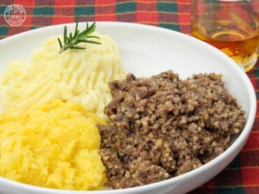 A plate of Vegan Haggis, made with lentils, oats, vegetables, and spices, served with traditional sides like mashed potatoes and turnips.