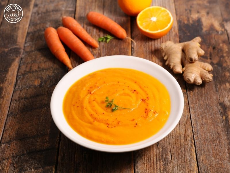 A bowl of Veggie Carrot Ginger Soup, showcasing vibrant orange carrots, fresh ginger, and a medley of vegetables in a warm, hearty broth.