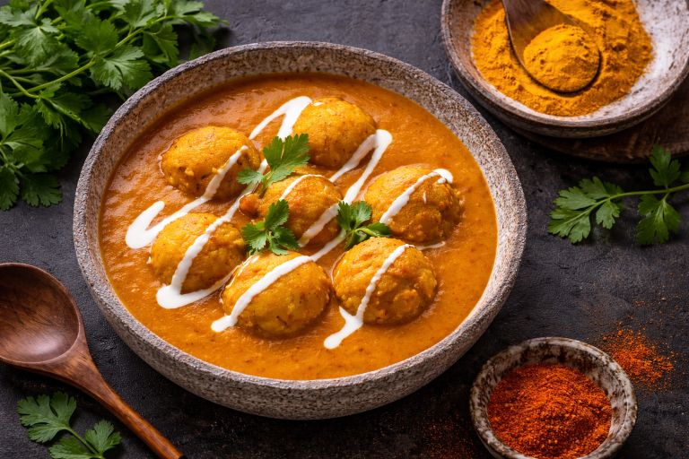 Cheesy mushroom malai kofta served in creamy restaurant style gravy with fresh coriander garnish