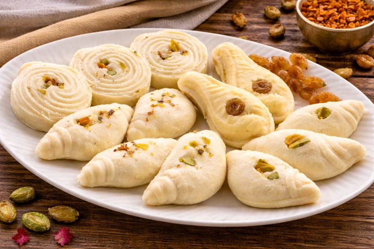 Assorted traditional Bengali sandesh sweets in different shapes with pistachio and raisin garnish
