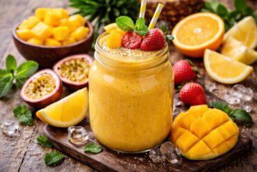 Sunburst Smoothie Recipe served in a glass jar with mango, orange, strawberry, and mint garnish