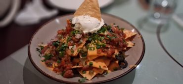 Veg fully loaded nachos with cheese sauce, black beans, salsa, jalapeños, and avocado