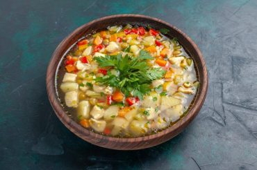 Bamboo shoot curry recipe served in rustic clay bowl with coriander garnish and steamed rice on wooden table