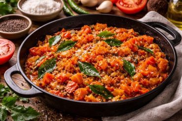 Tomato fry recipe Kerala style with curry leaves, spices, and coconut oil served in rustic pan
