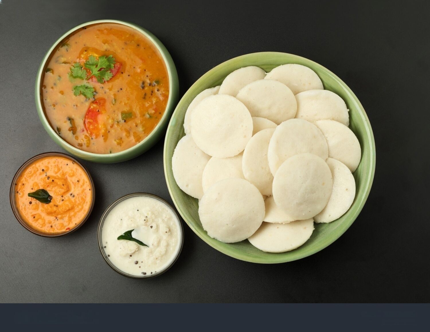 Idli recipe variations featuring steamed idli, thatte idli, podi idli, sambar idli, and mini button idli on rustic table
