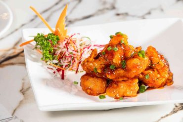 Crispy gochujang cauliflower garnished with sesame seeds and spring onions
