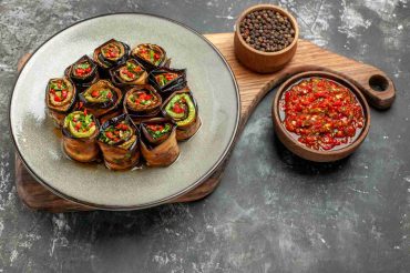 Vegan eggplant sushi rolls filled with sushi rice, crispy tofu, avocado, cabbage slaw, and pickled vegetables, garnished with sesame seeds and green onions.