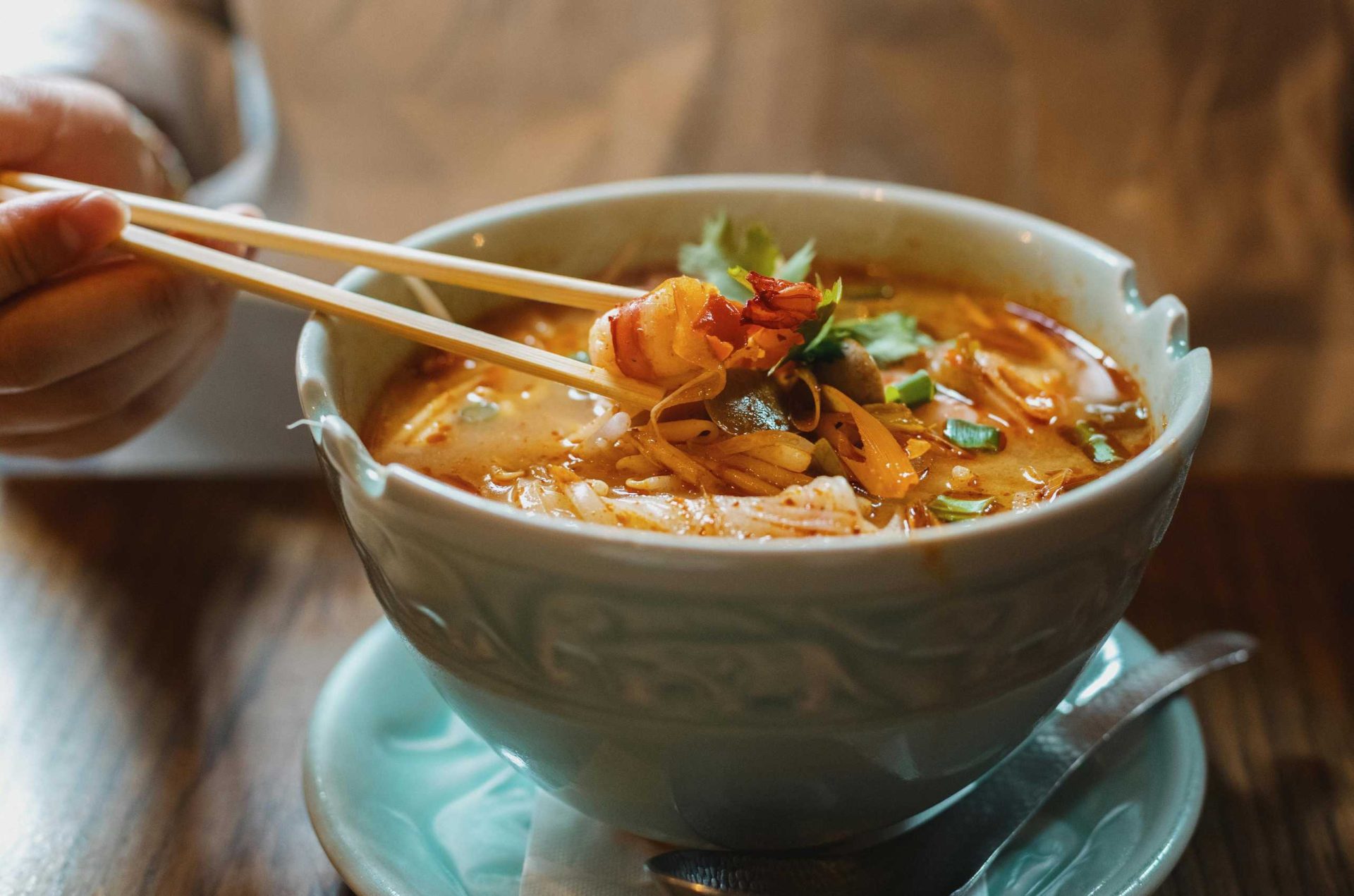 Bowl of Khao Soi, Northern Thai curry noodle soup topped with crispy noodles, chicken, lime, and fresh herbs.