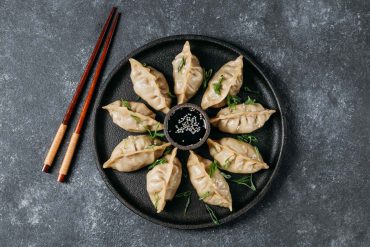 Scallion paneer momos served with chilli sauce and creamy dip on a plate