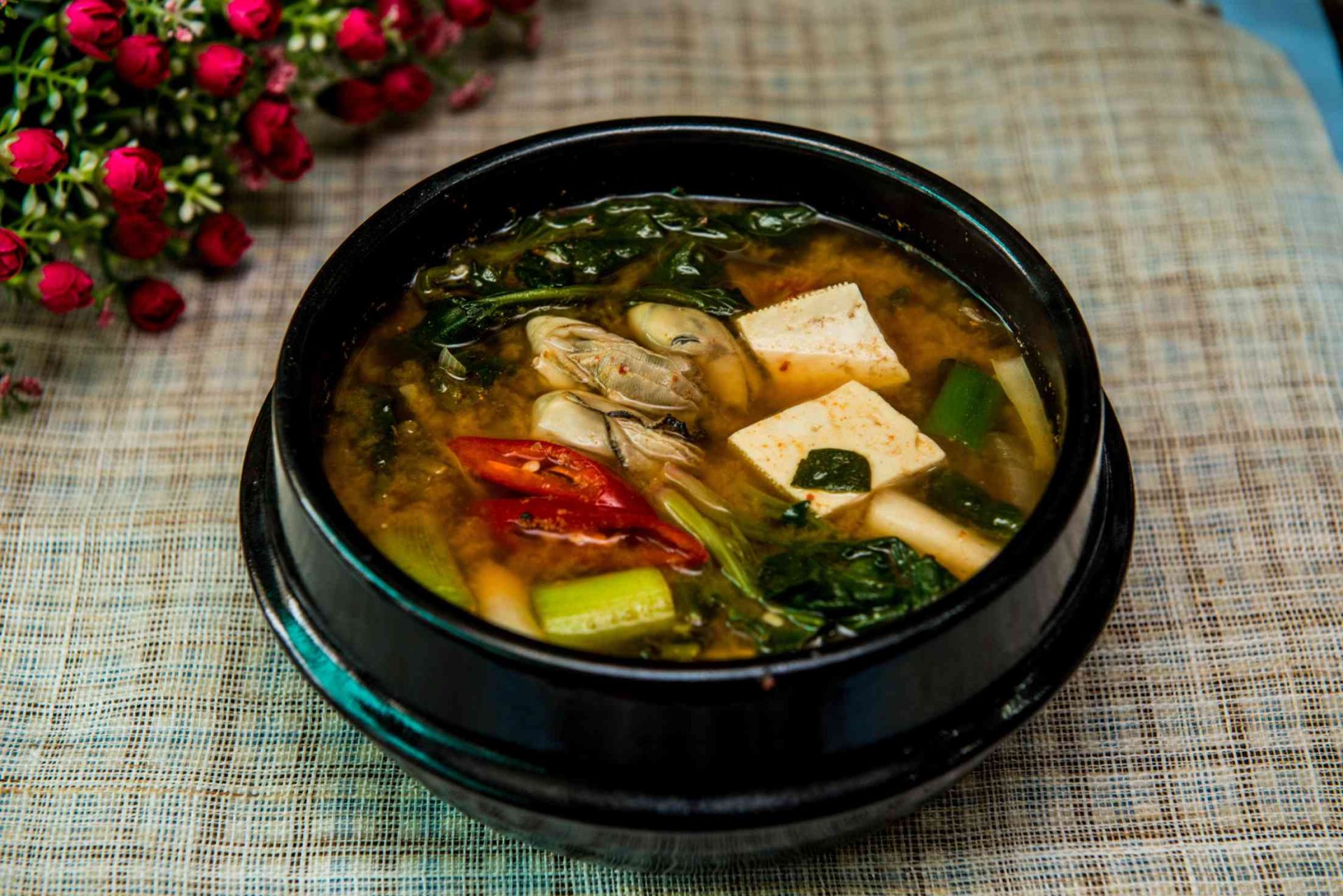 Steaming bowl of vegetarian miso soup with tofu, mushrooms, and green onions