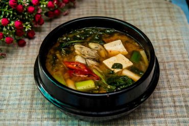 Steaming bowl of vegetarian miso soup with tofu, mushrooms, and green onions