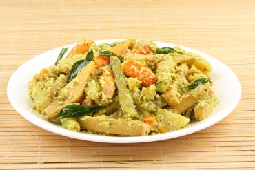 Avial recipe served in white plate with curry leaves and mustard seeds topping